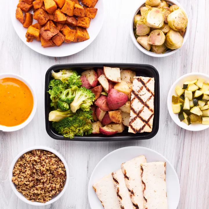 Sliced chicken with roasted red potatoes and broccoli in a meal prep tray