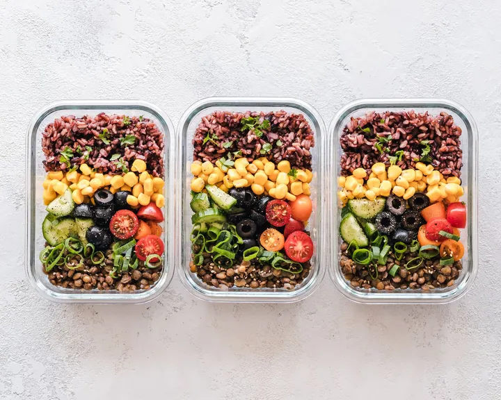 Three glass containers of lentils, black rice, chickpeas and vegetables