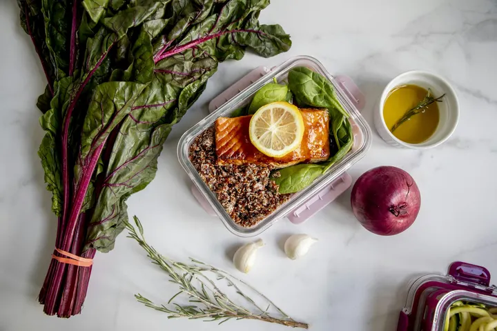 Glazed salmon over quinoa and spinach in a glass container